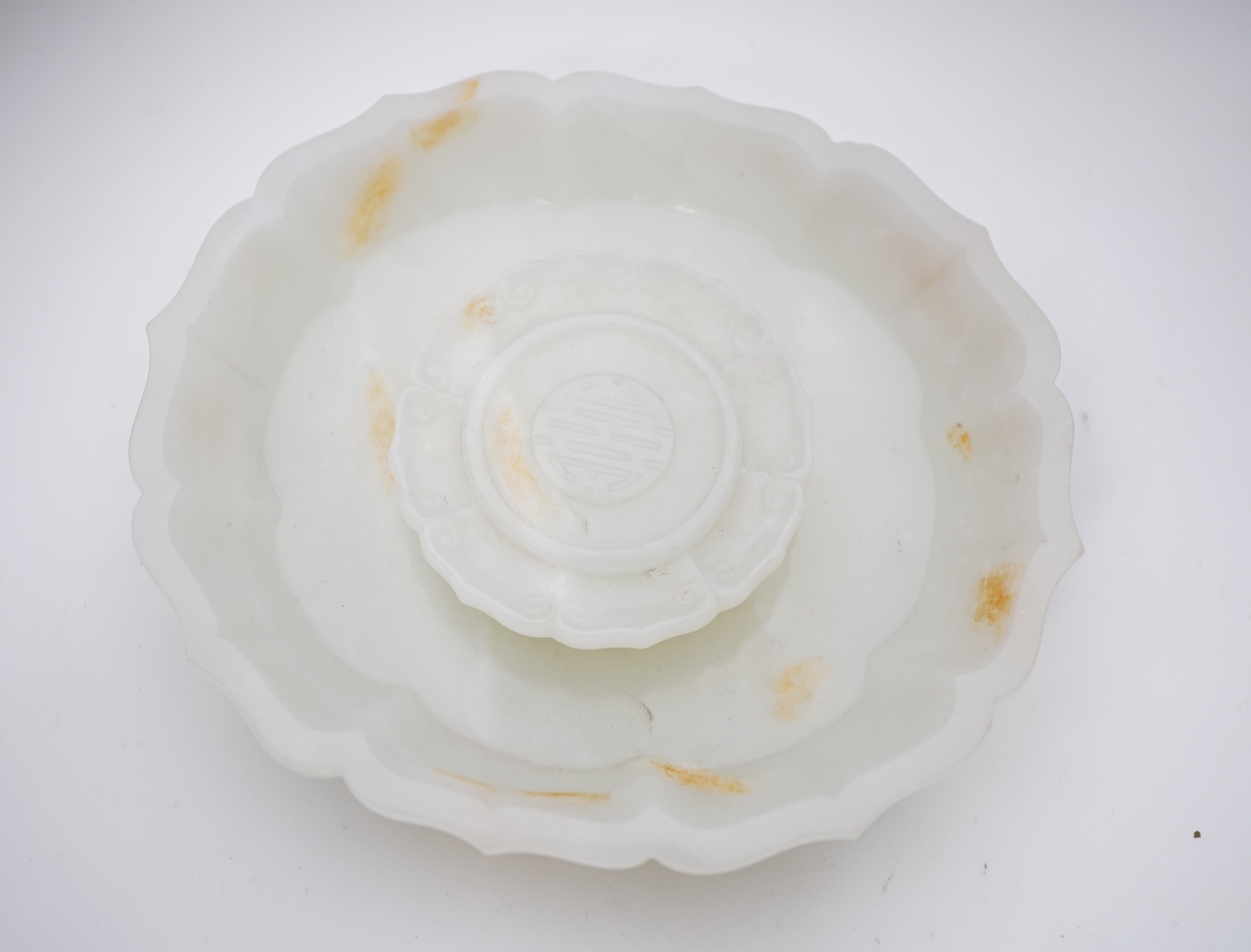 A Chinese white and russet jade petal lobed cup stand